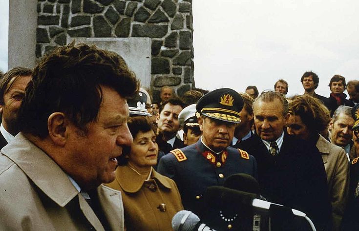 Franz Josef Strauß spricht vor dem Denkmal am Lago Llanquihue zur 125. Jahrfeier der deutschen Einwanderung nach Chile im November 1977, im Hintergrund das Ehepaar Pinochet