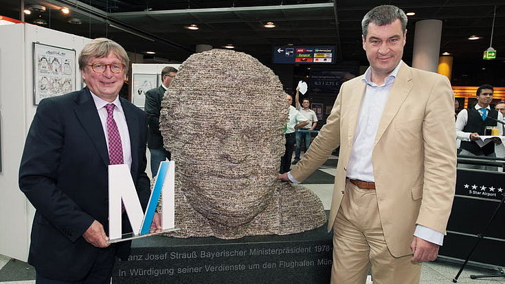 Dr. Michael Kerkloh, Vorsitzender der FMG-Geschäftsführung, und der damalige Heimatminister Markus Söder neben der Skulptur „FJS – ein bayerisches Urgestein“ von Hubert Maier